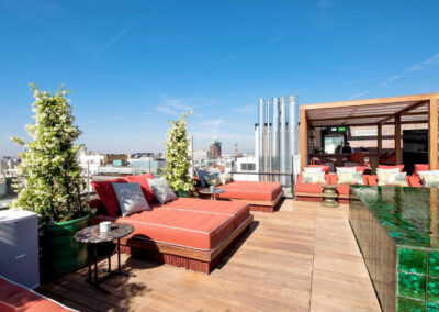 a patio with red couches and tables on a rooftop